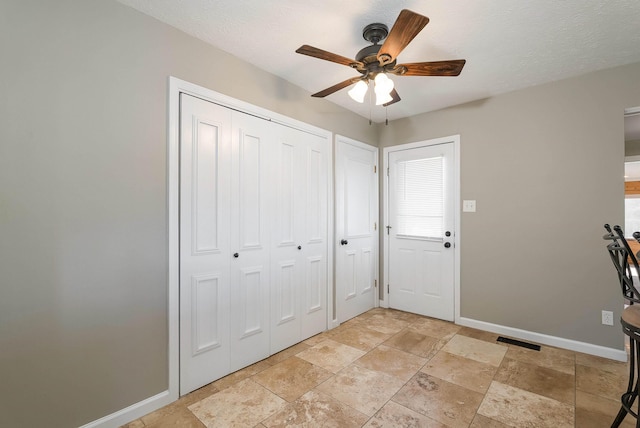 entrance foyer with baseboards, a textured ceiling, visible vents, and a ceiling fan