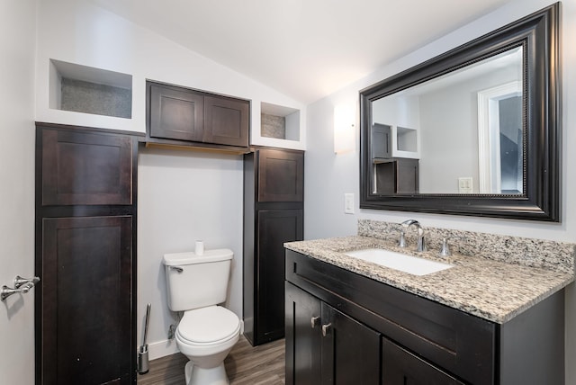 half bath with lofted ceiling, toilet, wood finished floors, vanity, and baseboards