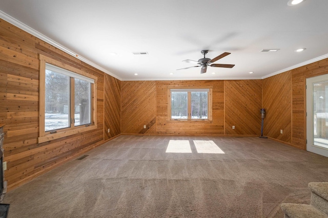 empty room featuring a healthy amount of sunlight, visible vents, ornamental molding, and light colored carpet