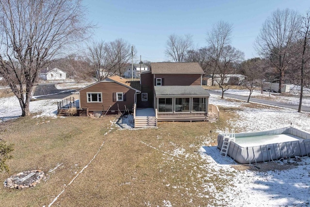 snow covered back of property featuring a sunroom