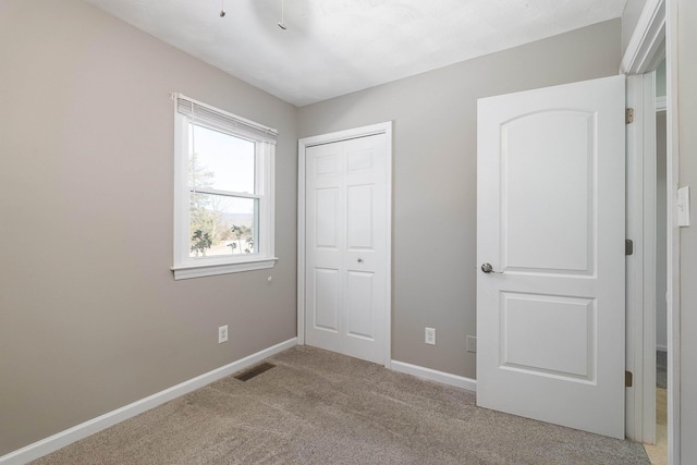 unfurnished bedroom featuring carpet floors, a closet, visible vents, and baseboards