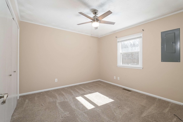 carpeted spare room with visible vents, ornamental molding, ceiling fan, electric panel, and baseboards