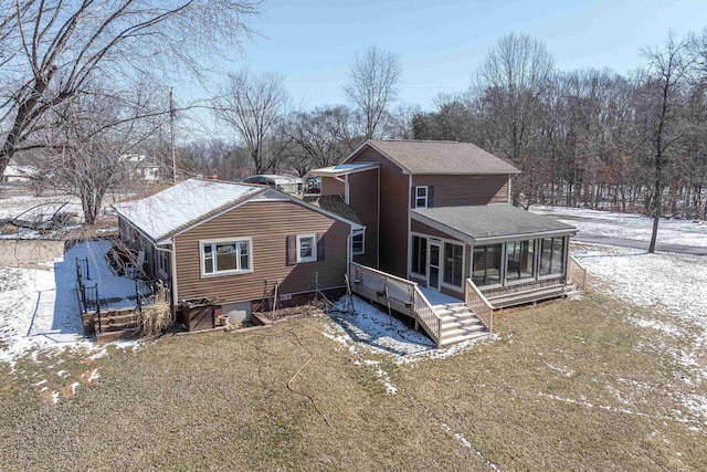 snow covered house featuring a sunroom and a shingled roof