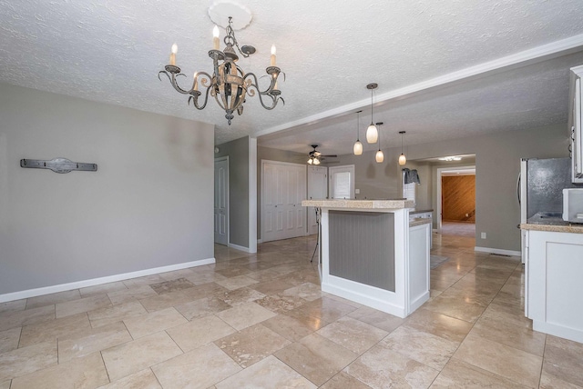 kitchen with baseboards, white cabinets, a textured ceiling, pendant lighting, and ceiling fan with notable chandelier