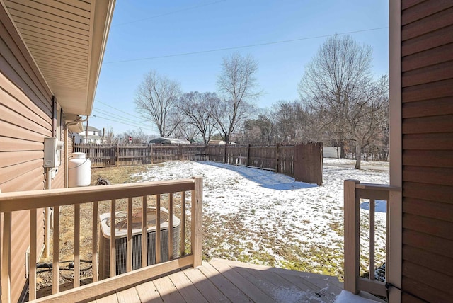 snow covered deck featuring central air condition unit and fence