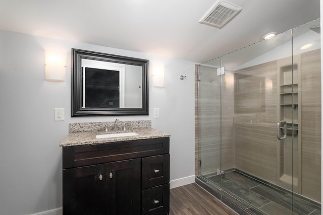 bathroom featuring lofted ceiling, visible vents, a stall shower, vanity, and wood finished floors