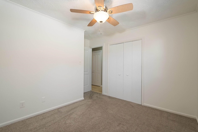 unfurnished bedroom with a textured ceiling, carpet floors, a closet, and crown molding