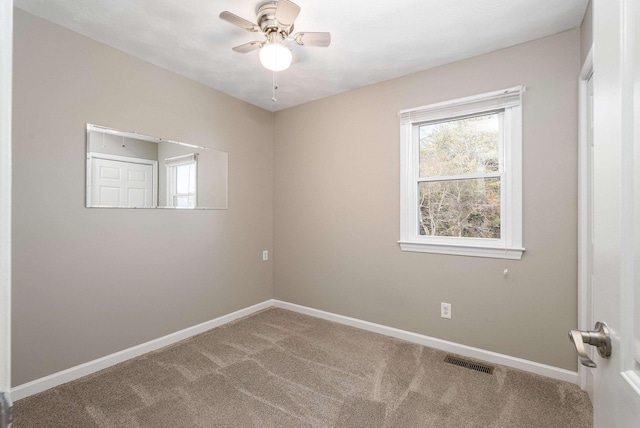 unfurnished room with carpet flooring, visible vents, and baseboards