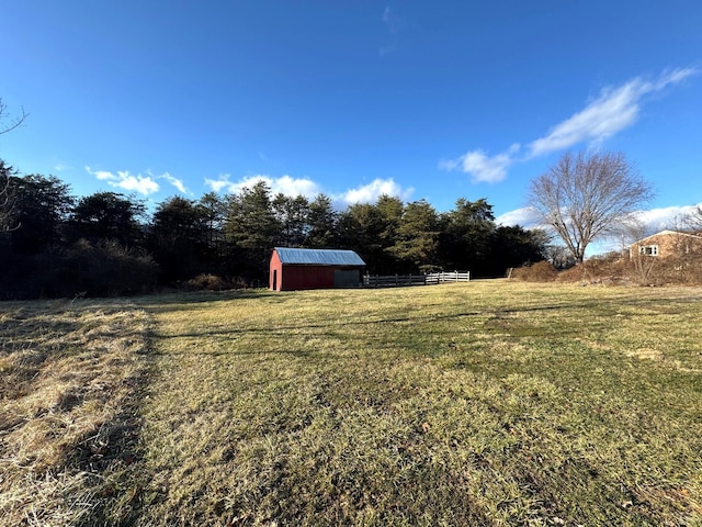 view of yard with a rural view, fence, and an outbuilding