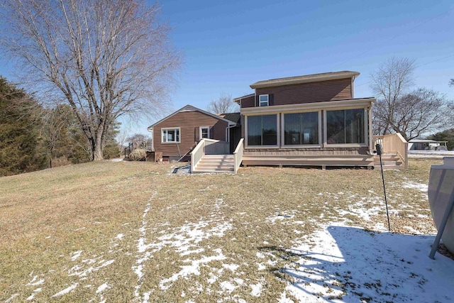 snow covered house featuring a wooden deck and a sunroom