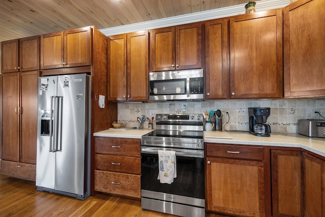 kitchen with stainless steel appliances, wood finished floors, light countertops, and decorative backsplash