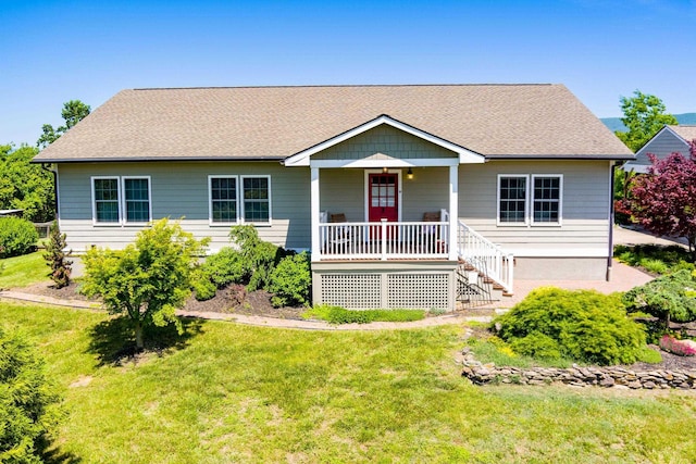 ranch-style house featuring covered porch, roof with shingles, and a front yard