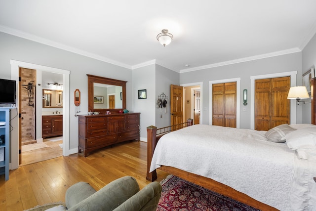 bedroom featuring two closets, light wood-style flooring, ensuite bathroom, ornamental molding, and baseboards