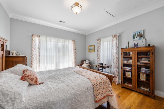 bedroom featuring visible vents, ornamental molding, multiple windows, and attic access