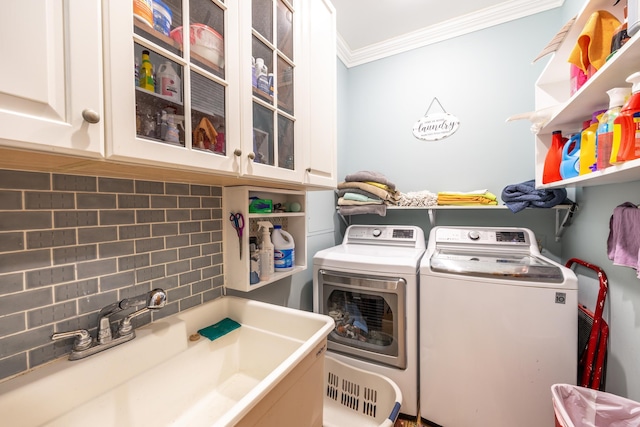 washroom featuring ornamental molding, separate washer and dryer, a sink, and cabinet space