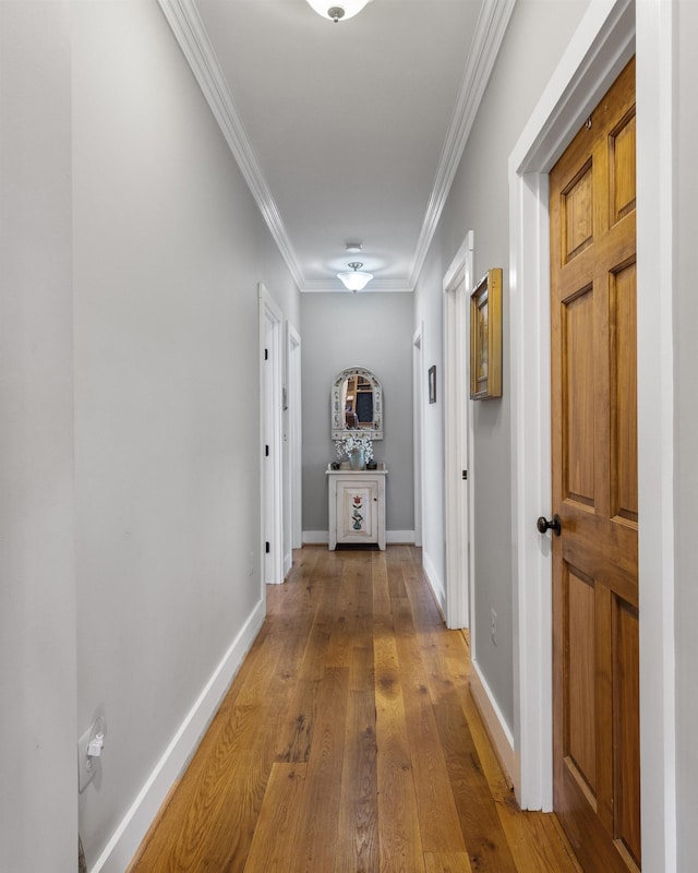 corridor featuring wood-type flooring, crown molding, and baseboards