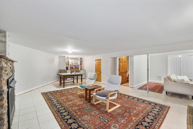 interior space featuring light tile patterned floors, baseboards, visible vents, and a large fireplace