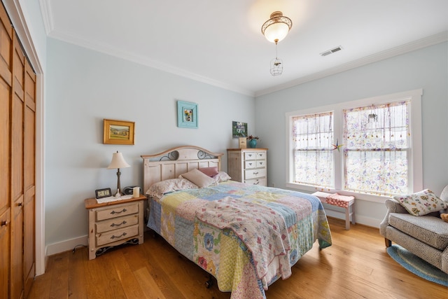 bedroom featuring a closet, wood-type flooring, visible vents, and crown molding