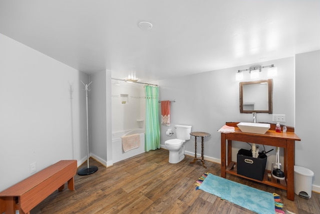 full bath featuring toilet, shower / tub combo, wood finished floors, a sink, and baseboards