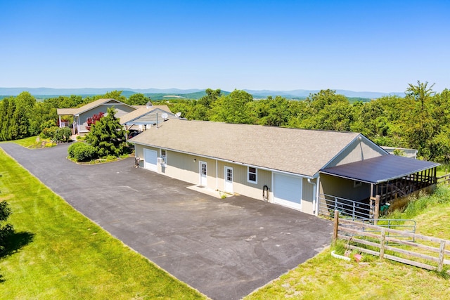 single story home with driveway, a detached garage, and a mountain view