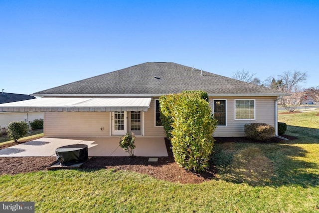 back of property with a yard, a patio, and a shingled roof