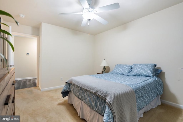 bedroom featuring baseboards, light colored carpet, and a ceiling fan