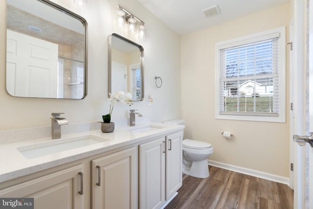 full bathroom featuring visible vents, toilet, wood finished floors, and a sink