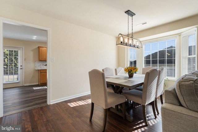 dining space featuring a chandelier, visible vents, dark wood-type flooring, and baseboards