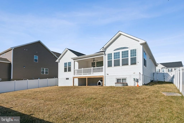 back of house featuring ceiling fan, a yard, a fenced backyard, and a gate