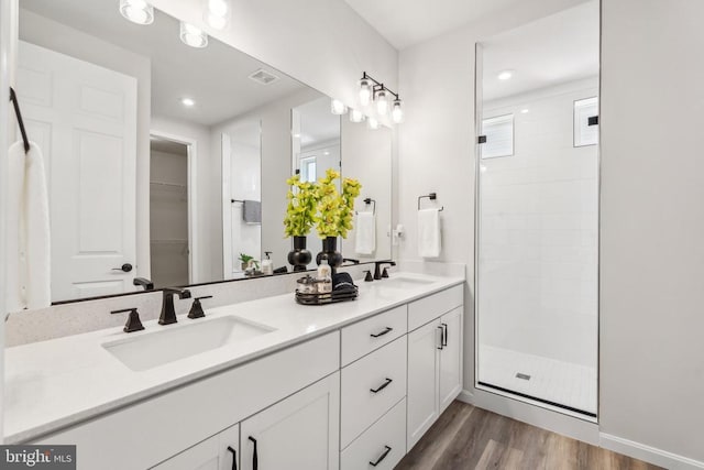 bathroom with wood finished floors, a sink, and a shower stall