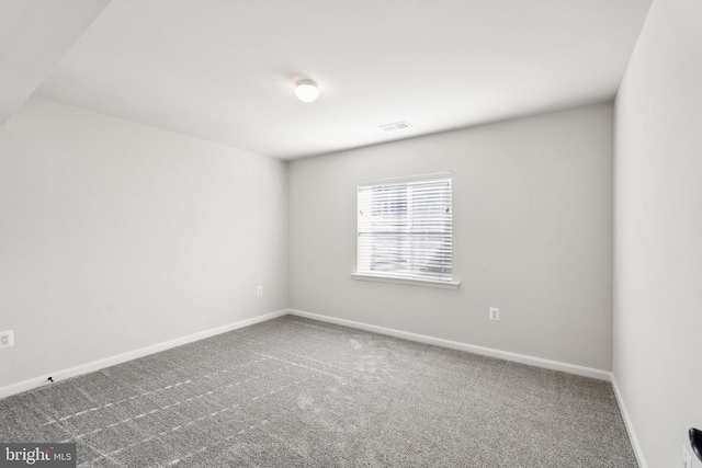 spare room with carpet floors, visible vents, and baseboards