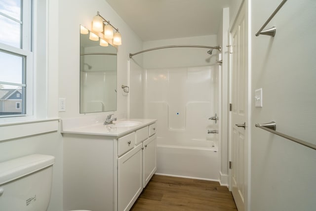 full bathroom with wood-type flooring, toilet,  shower combination, and vanity