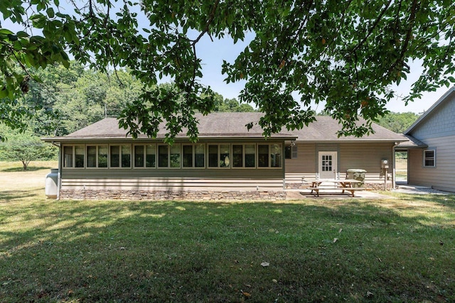 rear view of property with a sunroom, a patio area, and a lawn