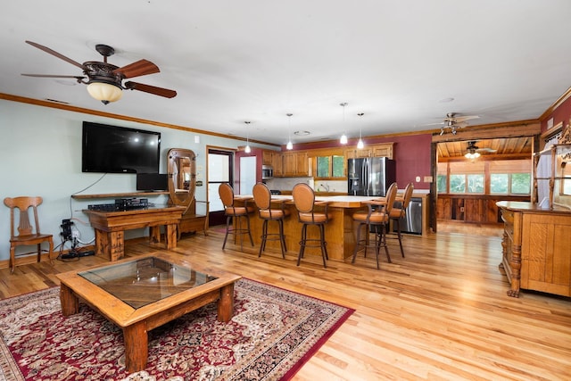 living room featuring crown molding, ceiling fan, and light wood-type flooring