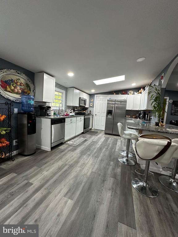 kitchen with stainless steel appliances, white cabinets, and light hardwood / wood-style flooring