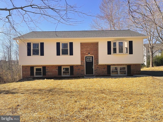 raised ranch with a front yard and brick siding