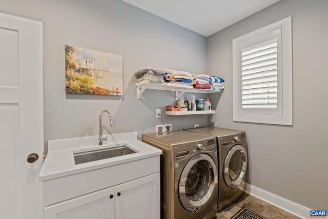 laundry area featuring cabinet space, washing machine and dryer, baseboards, and a sink