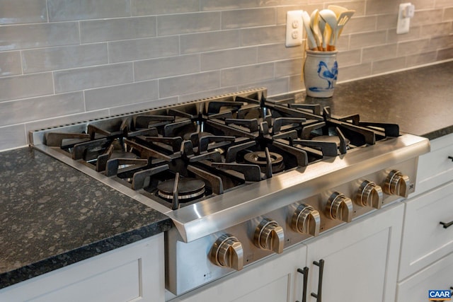 interior details with decorative backsplash, white cabinetry, and range