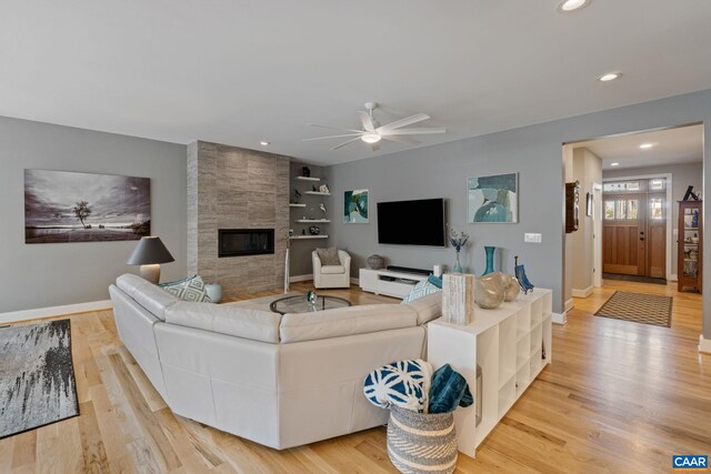 living room featuring a tiled fireplace, recessed lighting, baseboards, and light wood finished floors