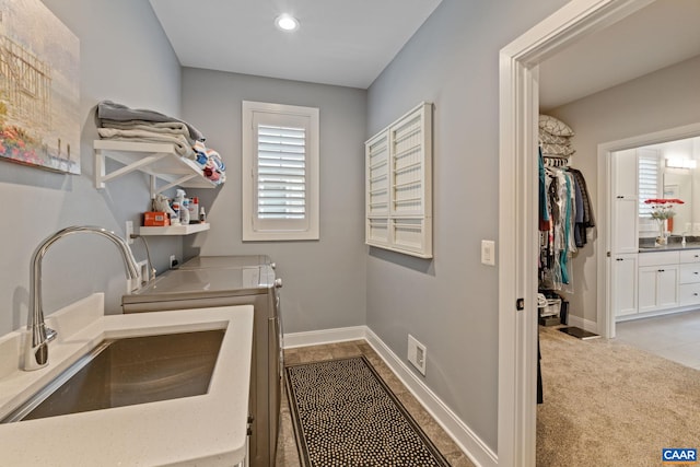 clothes washing area with a sink, carpet, baseboards, laundry area, and washing machine and clothes dryer