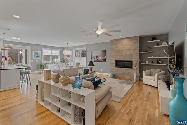 living area featuring a fireplace, light wood-type flooring, and baseboards