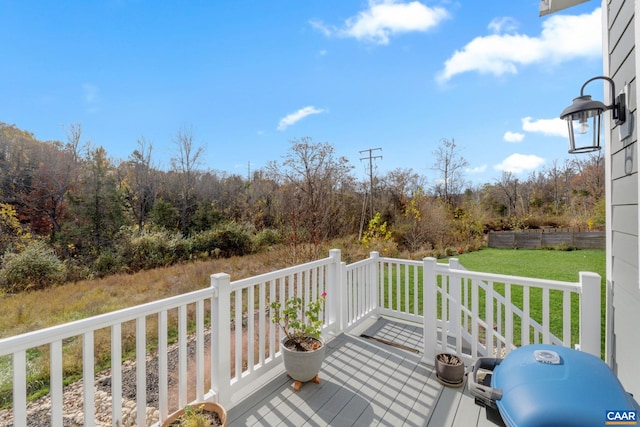 wooden deck featuring area for grilling, a lawn, and a forest view