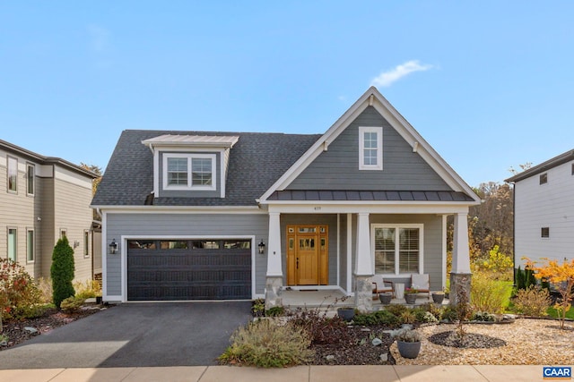 view of front of property featuring roof with shingles, a standing seam roof, covered porch, aphalt driveway, and metal roof