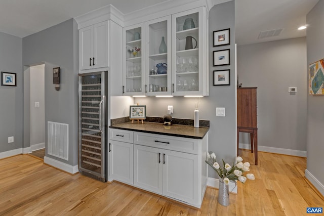 bar featuring light wood-type flooring, visible vents, wine cooler, and a bar