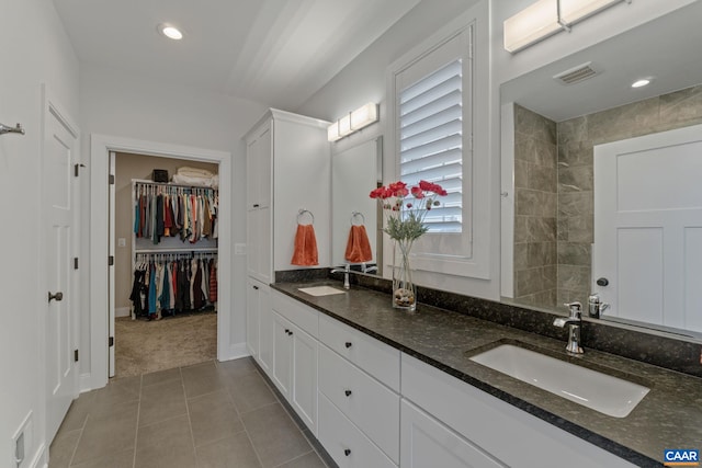 bathroom featuring a sink, visible vents, a spacious closet, and double vanity