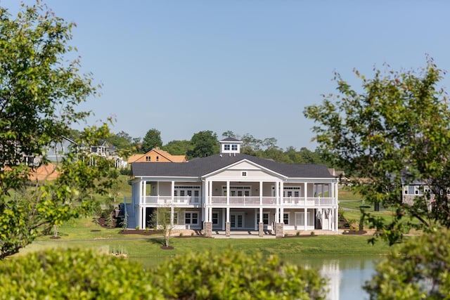 back of house featuring a patio area, a lawn, a balcony, and a water view