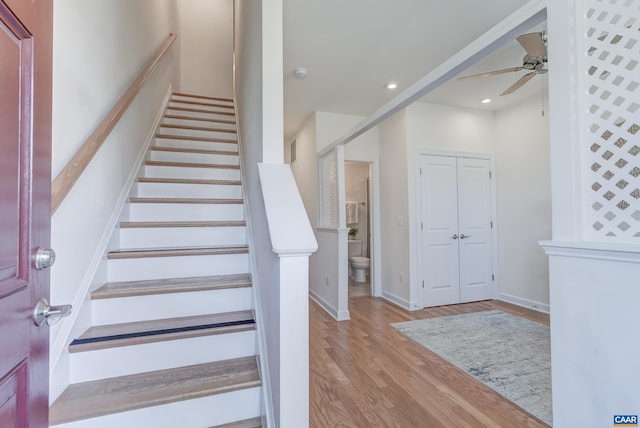 stairway with hardwood / wood-style flooring and ceiling fan