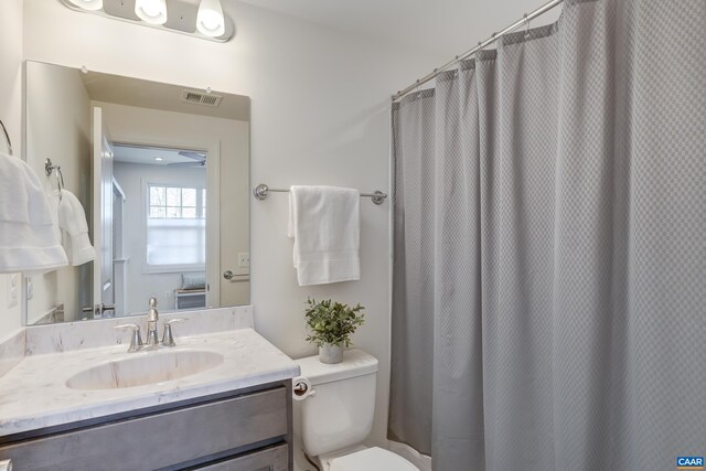 bathroom featuring vanity, walk in shower, and toilet