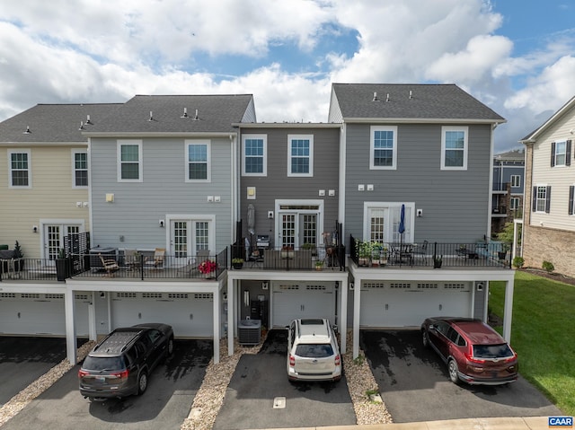 back of property with french doors, a balcony, a garage, and central AC unit