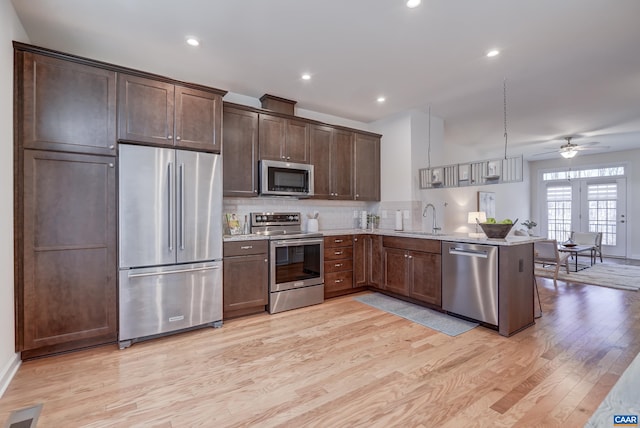 kitchen featuring sink, light stone counters, kitchen peninsula, pendant lighting, and stainless steel appliances